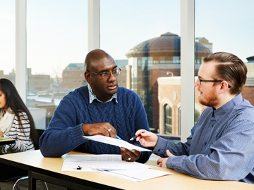 staff and student talking in front of window