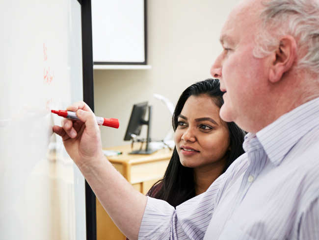 student standing with professor at white board
