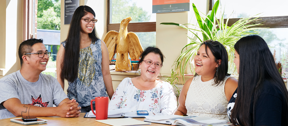students sitting around table with faculty conversing
