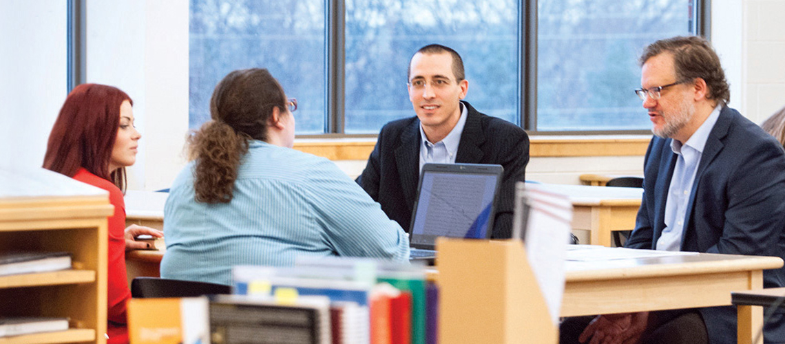 students speaking with professors at table