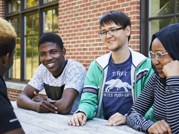 students sitting a picnic bench conversing