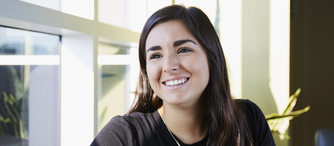 student smiling next to window