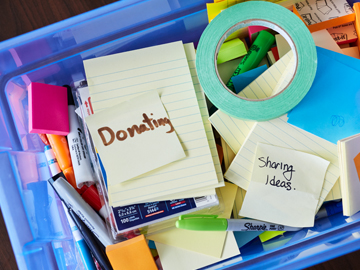 plastic bin filled with supplies, post-it notes with the words 