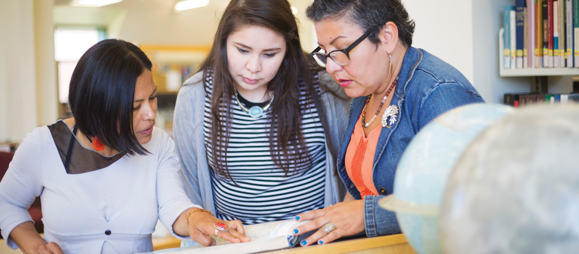 professors and student looking at book