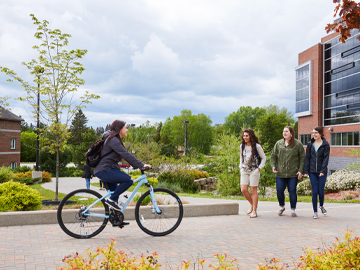 student riding bike in one direction with three students walking opposite