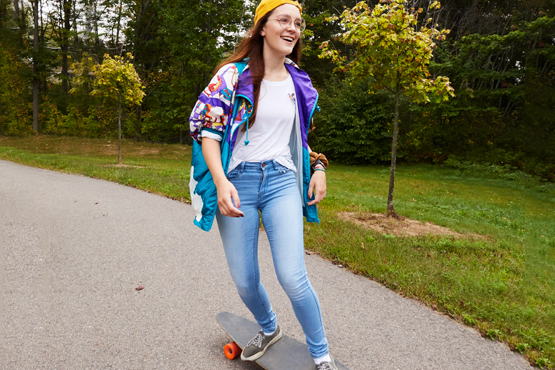 student riding longboard down path