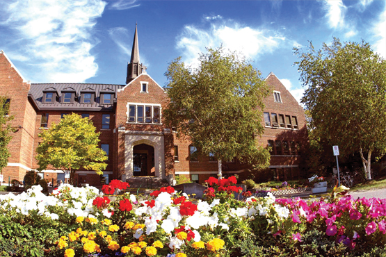 front steps of Shingwauk hall surrounded by flowers and trees