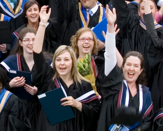 students at graduation throwing caps in air