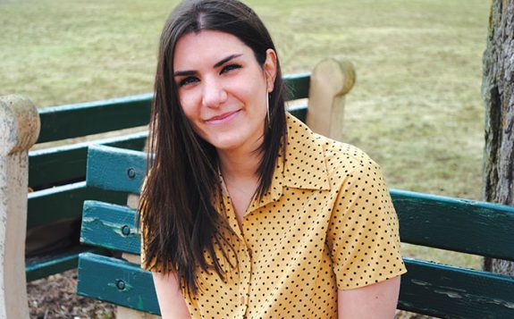 student smiling while sitting on bench