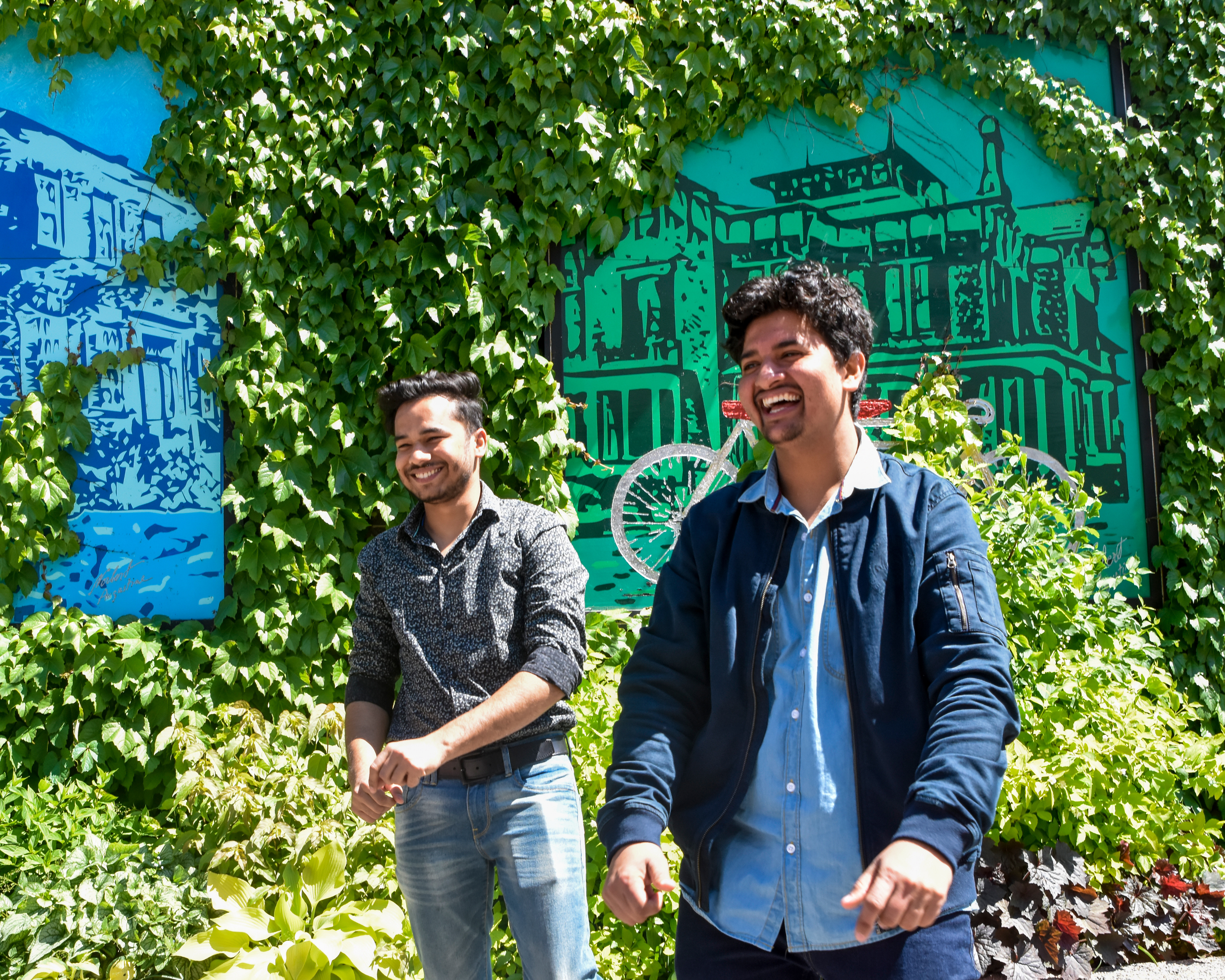 two students laughing outdoor near decorated wall in Brampton