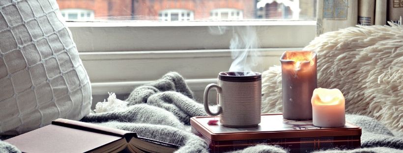 coffee mug, text book and two candles on a table