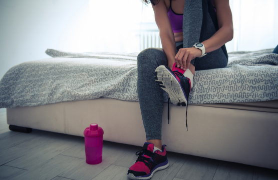 student wearing a shoe by sitting on a bed and a water bottle on the floor
