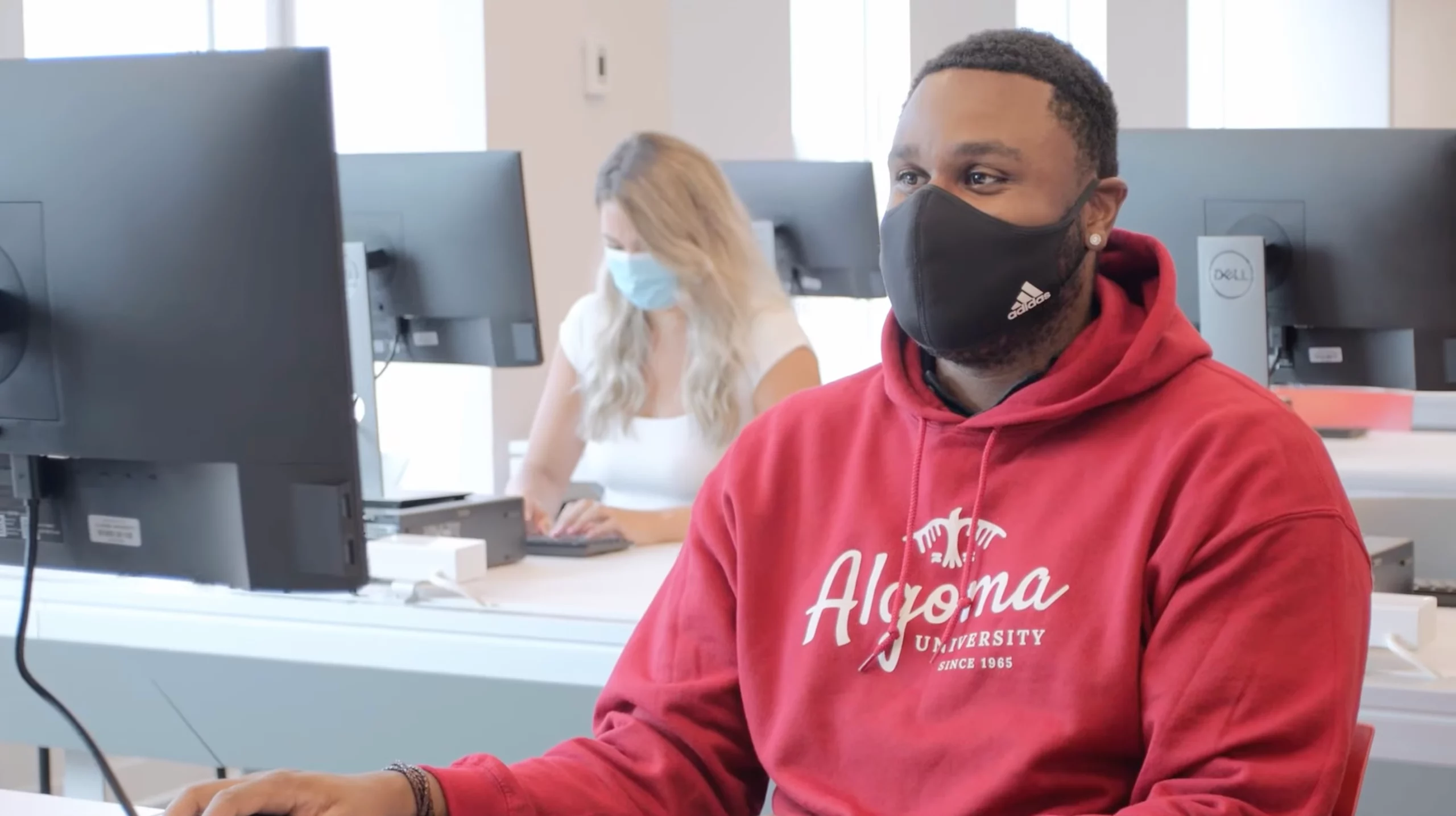 Student in computer lab wearing Algoma U sweater