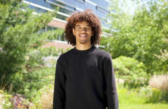 Algoma U student, Jahiem smiling on campus trail with foliage in the background